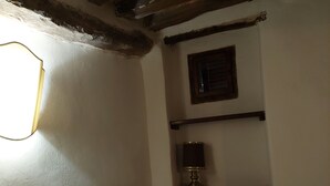 Ein Zimmer mit einem hölzernen Bett, einem kleinen Nachttisch mit Lampe und einem Regal mit Spiegel.