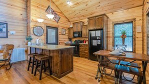 L’intérieur d’une cabane en bois comprend une cuisine, un coin repas et des tabourets de bar.