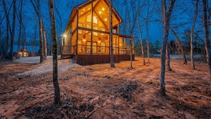 A wooden cabin with large windows and a covered porch, surrounded by trees. - Driftaway Lodge | Luxury Broken Bow Cabin with Game Room, Hot Tub & Fire Pit (Broken Bow)