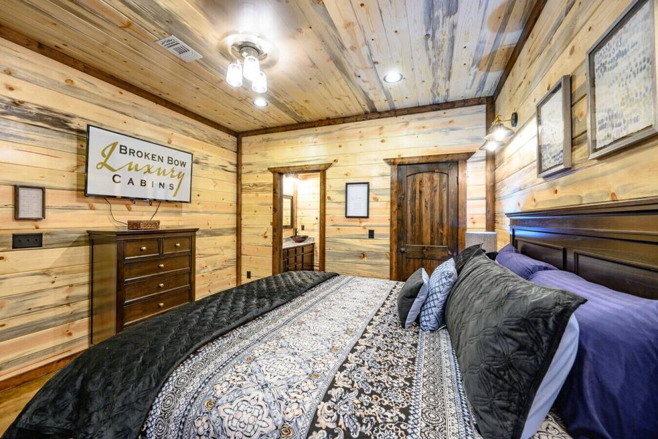 Ein schlafzimmer im Stil einer Blockhütte mit Bett, Kommode und einem Schild mit der Aufschrift 'Broken Bow Luxury Cabins'.