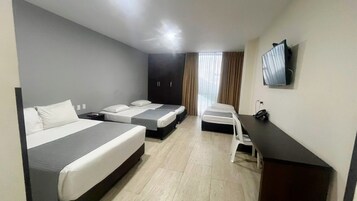 Habitación de hotel con dos camas, un escritorio, una silla, un televisor y una ventana con cortinas.