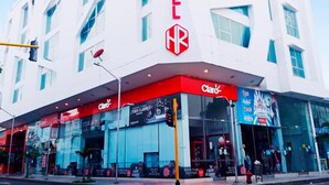 Un hotel moderno con un llamativo letrero 'HOTEL', una tienda 'Claro' y un cielo azul despejado al fondo.
