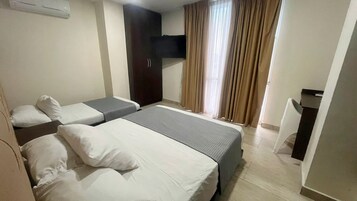 Habitación de hotel con dos camas, televisión, armario y escritorio.