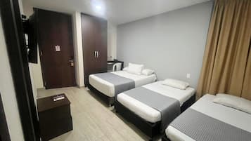 Habitación de hotel con dos camas individuales, un escritorio con silla, armario y televisor.