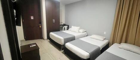 Habitación de hotel con dos camas individuales, un escritorio con silla, armario y televisor.