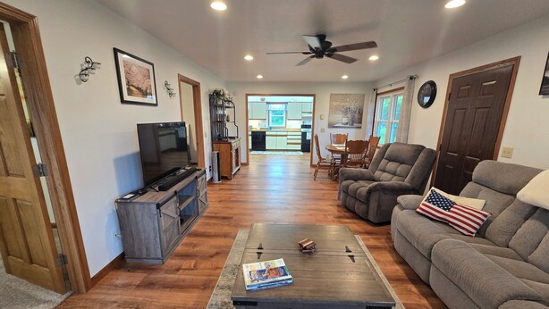 A living room with a television, a coffee table, a sofa, and a dining area in the background. - Hillsboro Driftless Guesthouse is cozy and ready for you! (Hillsboro)