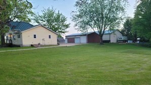A residential area with a large grassy yard, a yellow house, and a red garage. - Hillsboro Driftless Guesthouse is cozy and ready for you! (Hillsboro)