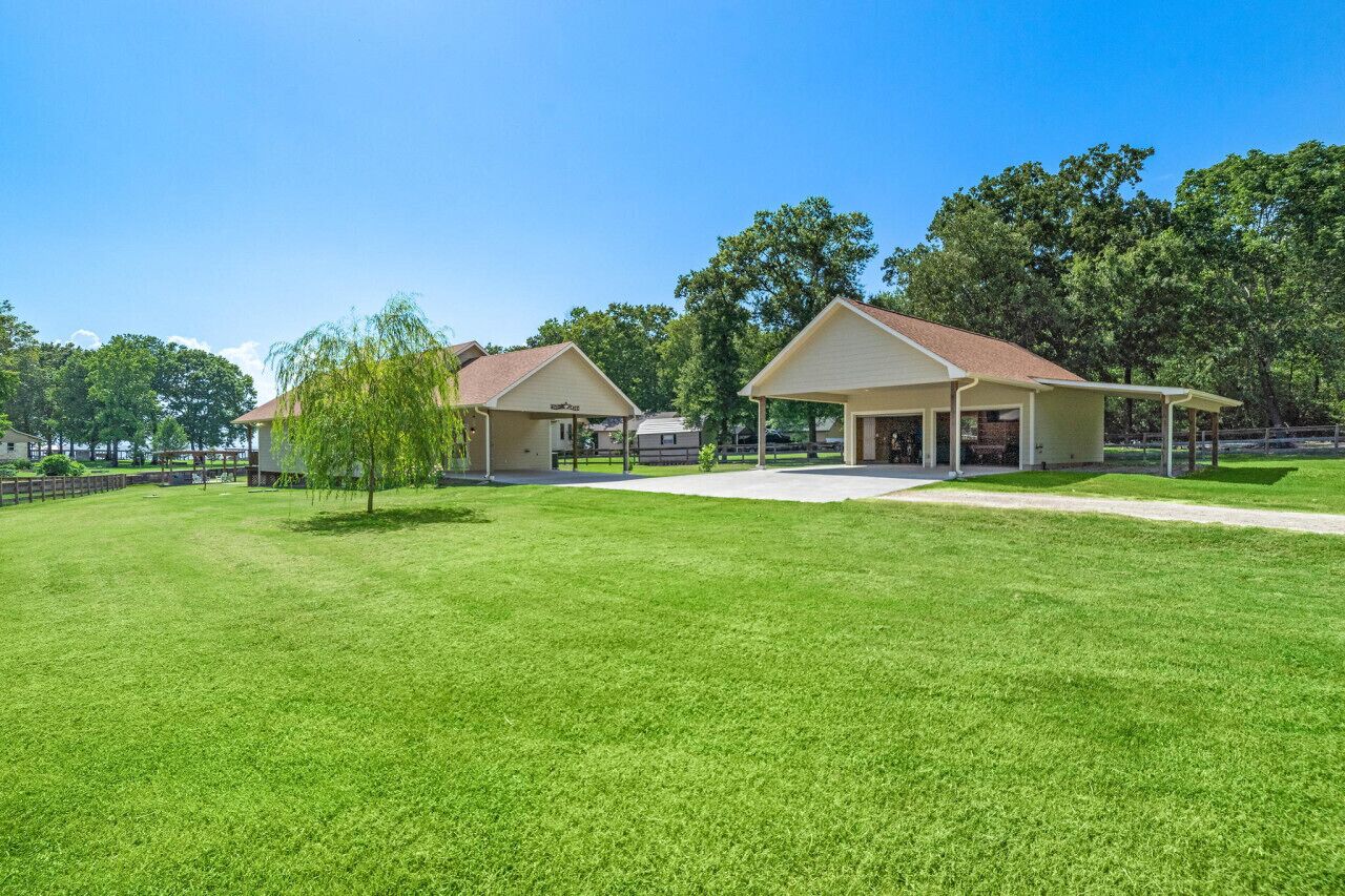 A residential area with two single-story houses, each with a covered porch, surrounded by well-maintained lawns and trees.