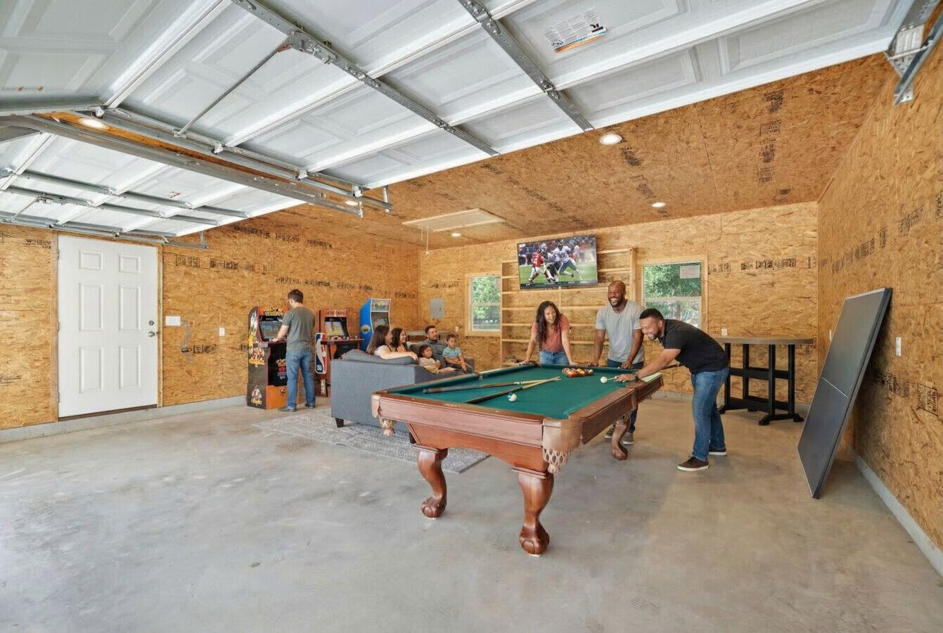 Une table de billard dans une pièce aux murs en bois et au sol en béton.