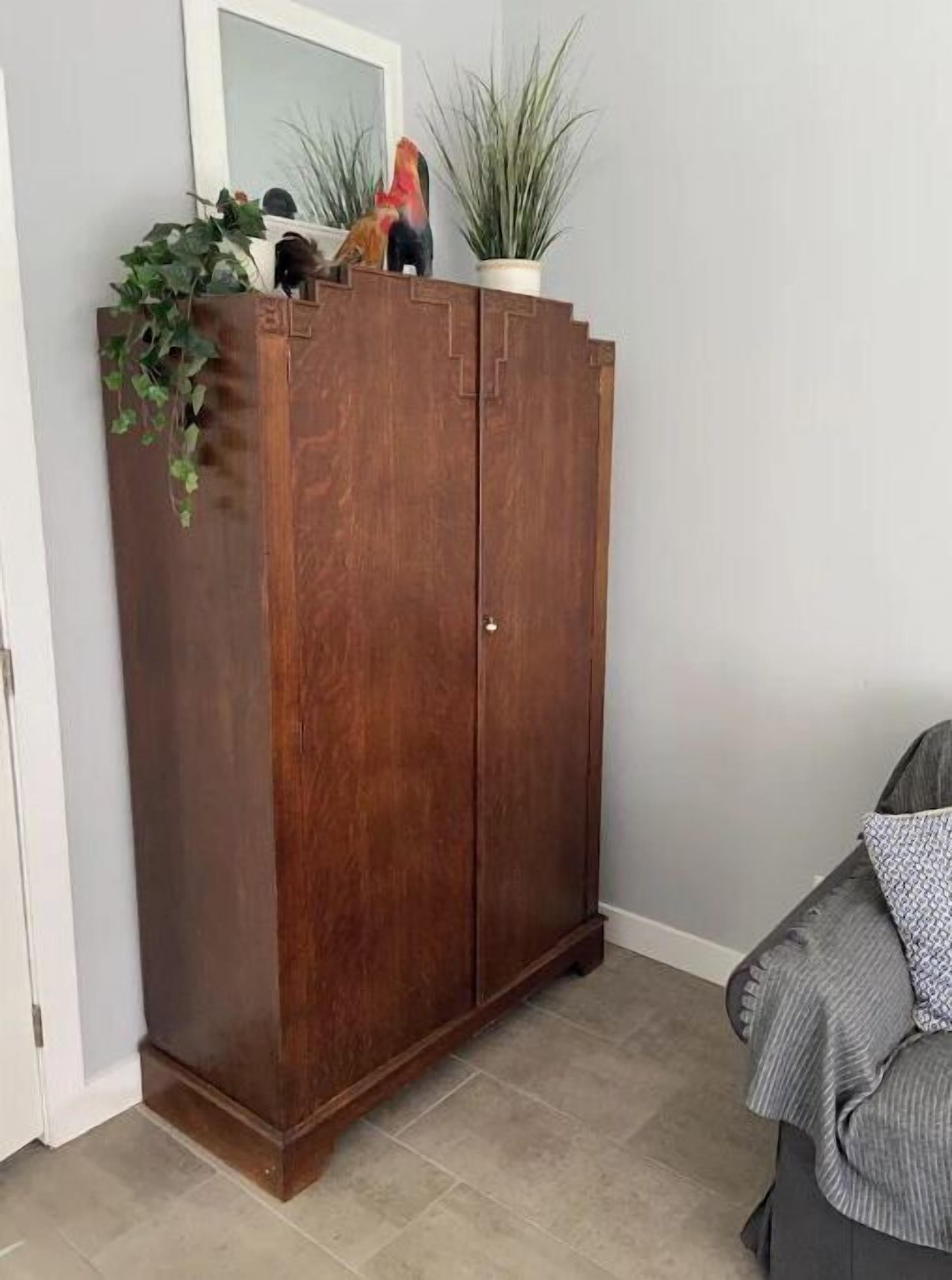 A wooden wardrobe with a mirror and decorative items.
