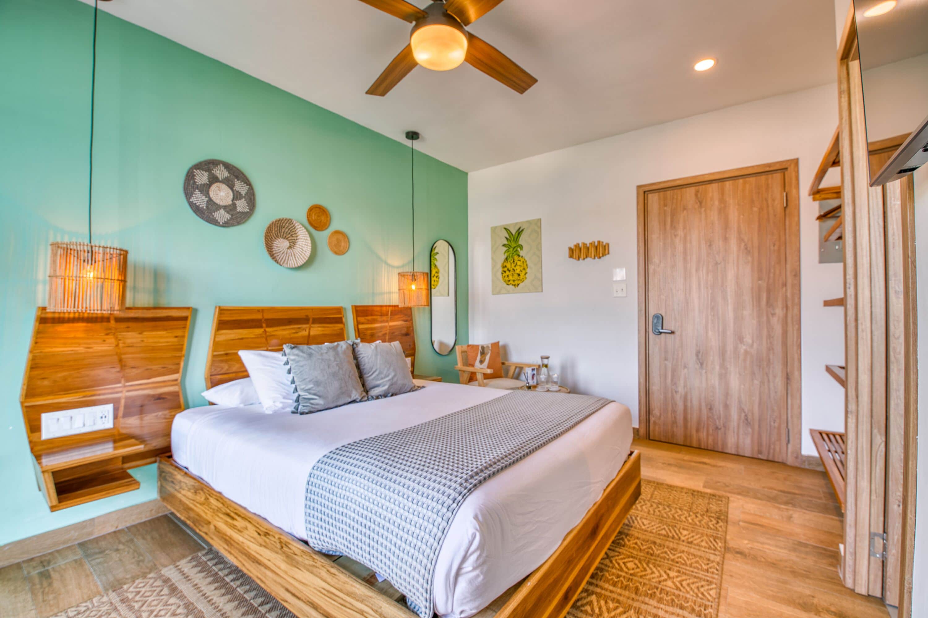 A bedroom with a wooden bed, a ceiling fan, and a wooden door.