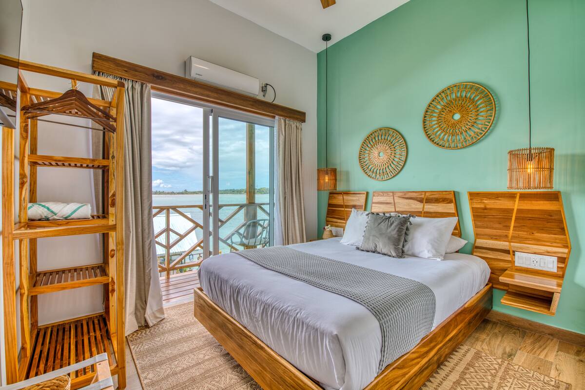 A bedroom with a large bed, wooden headboard, and a balcony with a view.