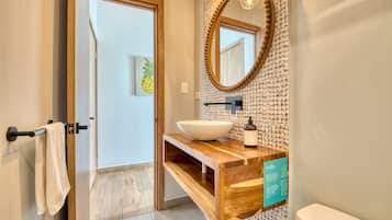 A modern bathroom with a wooden vanity, a large mirror, and a white sink.