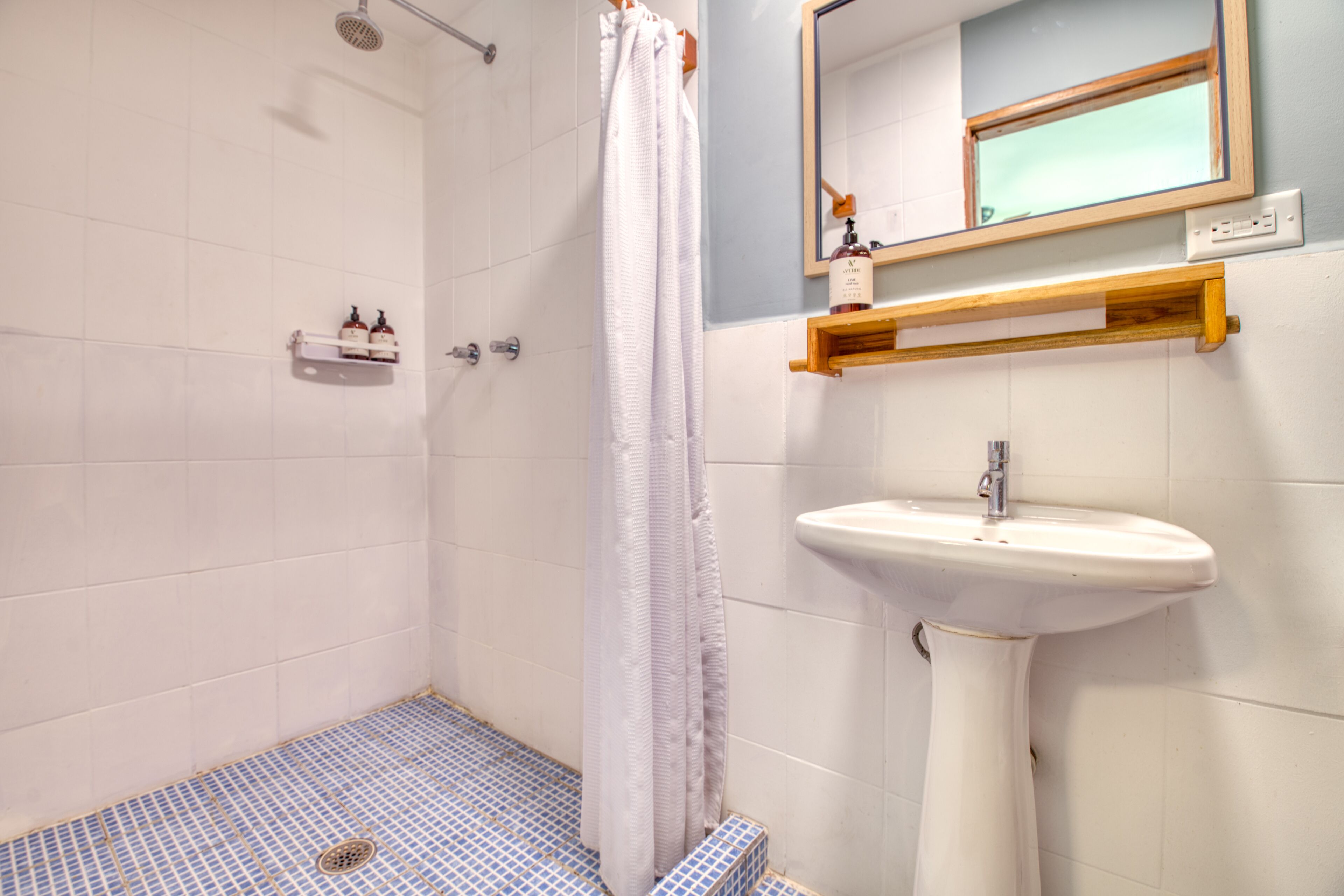 A bathroom with a shower, a sink, and a mirror.