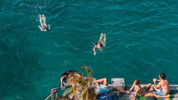 Un muelle de madera con gente nadando en el agua.