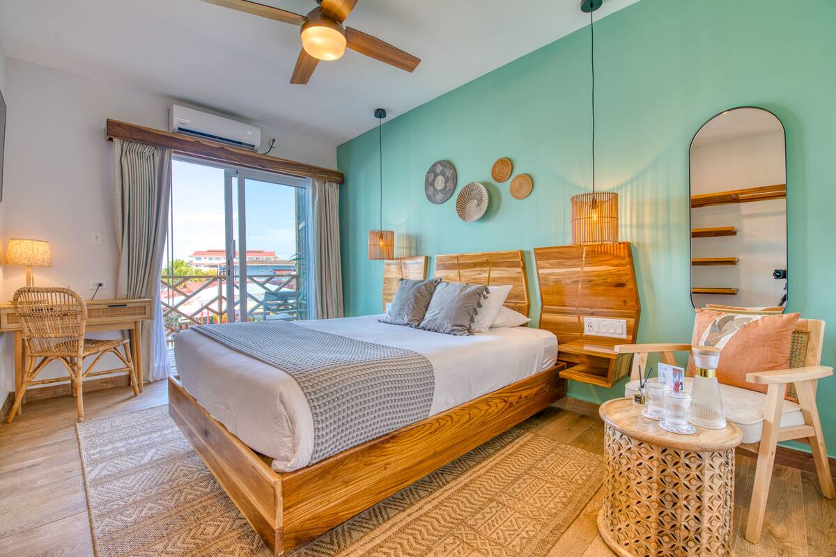 A bedroom with a wooden bed, a desk, a chair, a round table, and a ceiling fan.