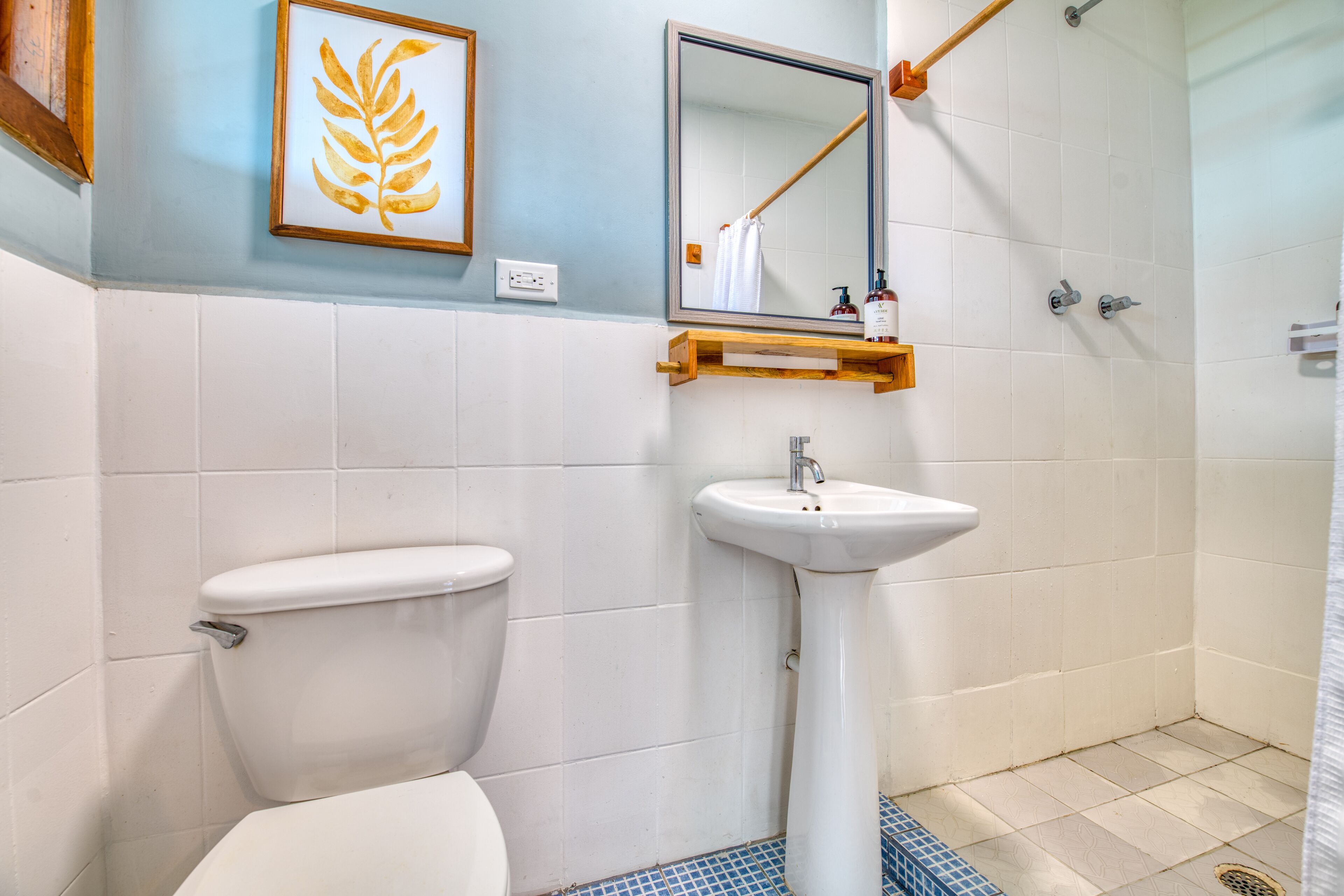 A bathroom with a toilet, sink, mirror, and shower.