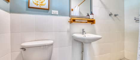 Une salle de bain équipée de toilettes, d’un lavabo, d’un miroir et d’une douche.
