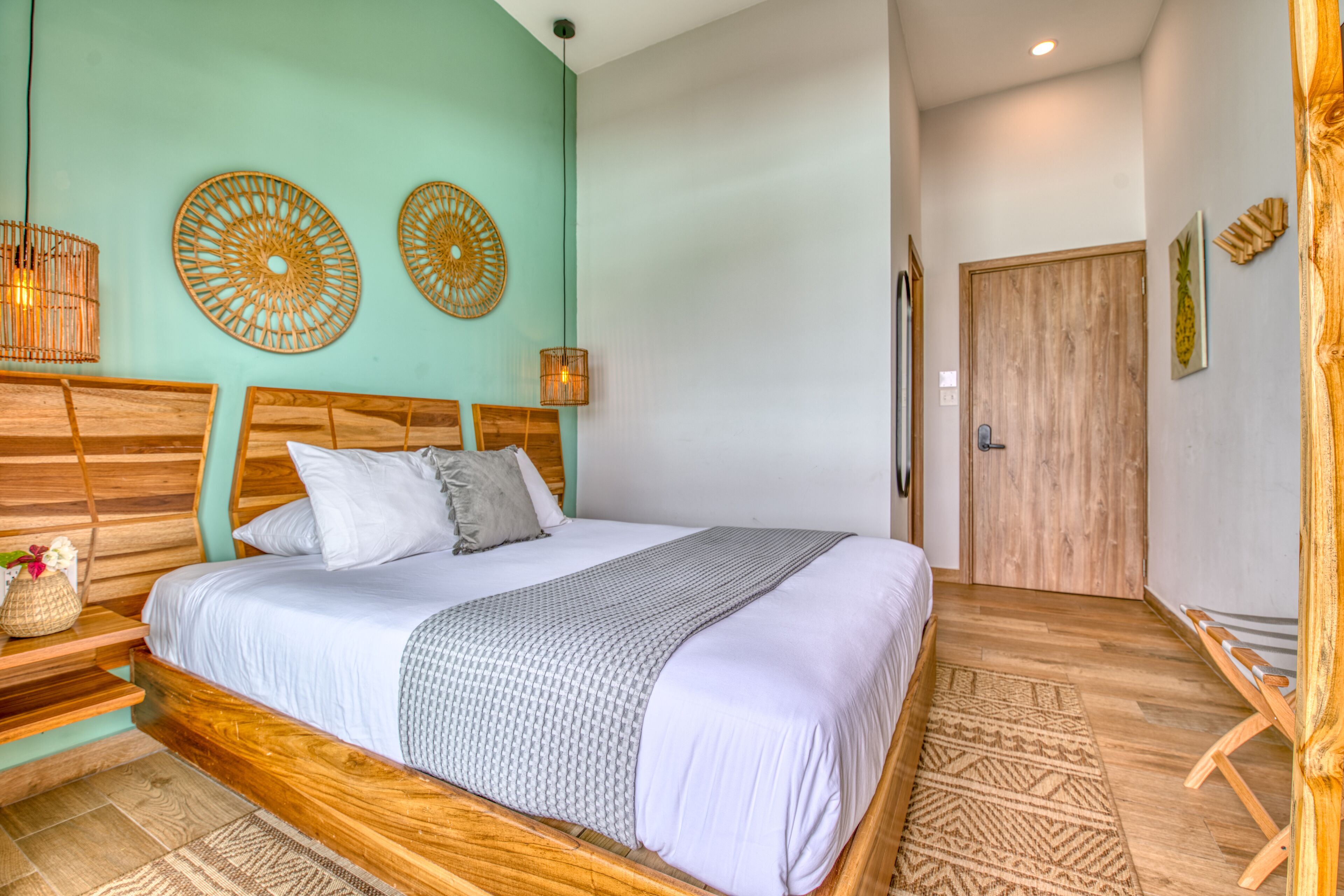 Un dormitorio con cama de madera, pared color turquesa y puerta de madera.