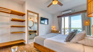 Un dormitorio moderno con cama de madera, ventilador de techo, televisor y una ventana grande con cortinas.