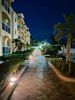 A pathway leading to a building with multiple balconies, surrounded by well-maintained greenery and palm trees. - Ria Aparta Hotel (Puerto Plata)