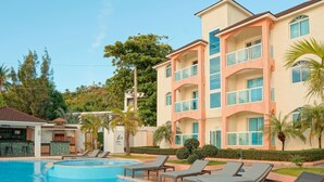A hotel with a swimming pool, lounge chairs, and a bar area. - Ria Aparta Hotel (Puerto Plata)