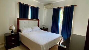 Een hotelkamer met een bed, nachtkastjes, een spiegel en een raam met gordijnen.