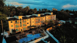 A hotel with multiple balconies, a swimming pool, and a view of the ocean. - Ria Aparta Hotel (Puerto Plata)