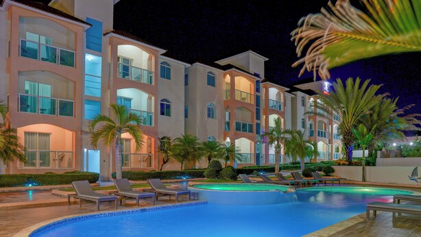 Un hôtel doté d’une piscine, de chaises longues et de palmiers.