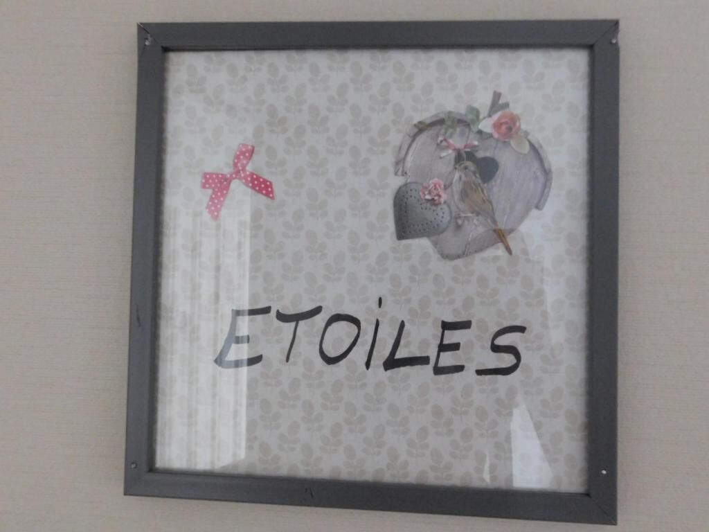 A framed picture with the word "ETOILES" and decorative elements including a bird and flowers.