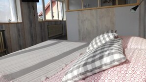 Un dormitorio con una cama, un televisor montado en la pared y una ventana con cortinas.