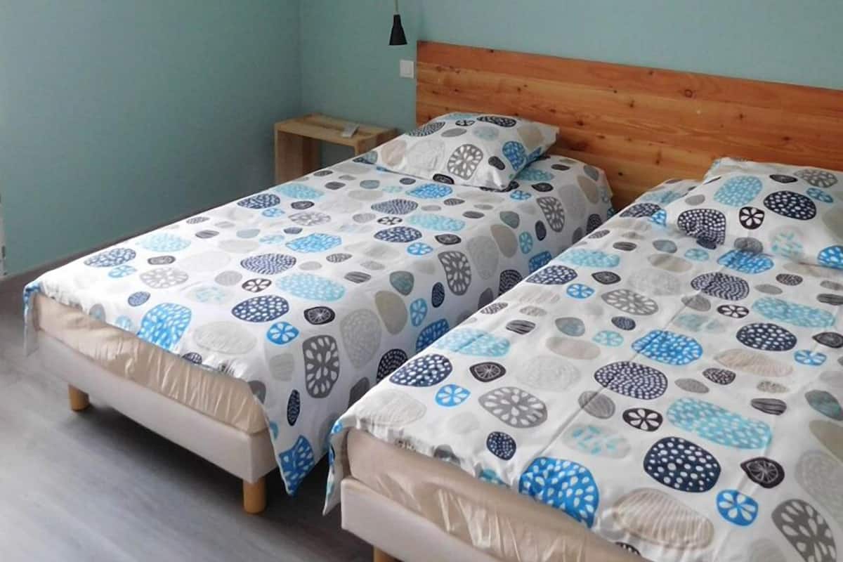 Une chambre à coucher avec deux lits, chacun agrémenté d’une couvre-lit à motifs, d’une tête de lit en bois et d’une petite table de chevet.