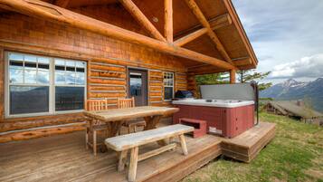 Een houten chalet met terras, een jacuzzi en uitzicht op de bergen.
