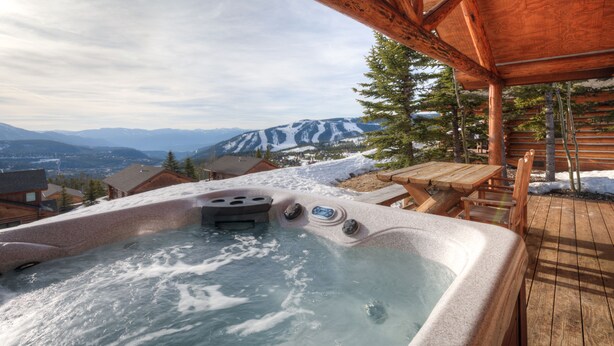 Ein Whirlpool mit Holzterrasse und Bergblick.