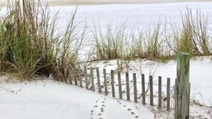 A sandy beach with a wooden fence and tall grasses. - SEA SHANTY- Beachfront, Topnotch Comfort & Fully-Stocked! (Mexico Beach)