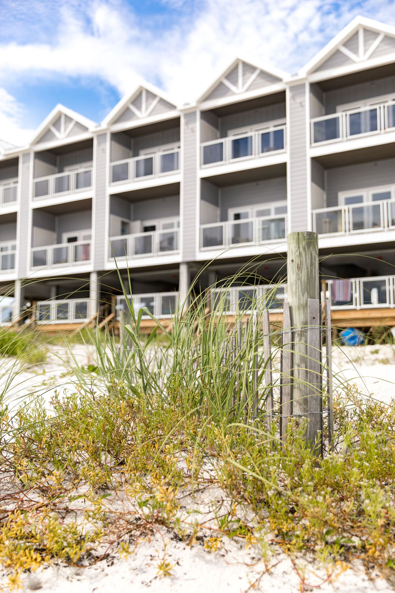 A beachfront hotel with multiple balconies and a sandy foreground.