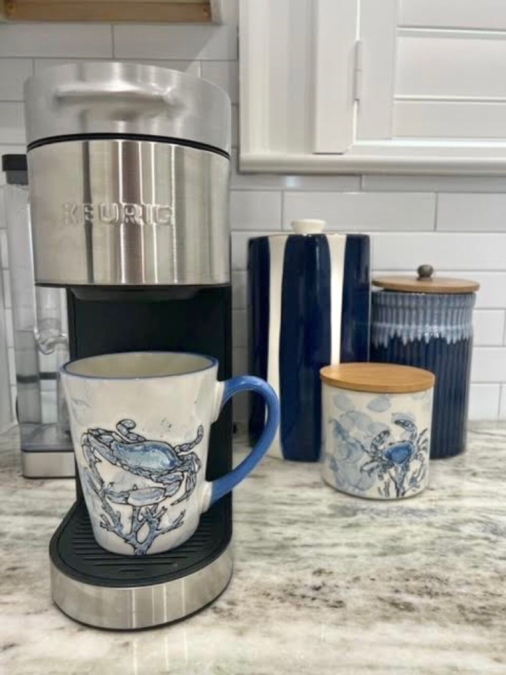 A kitchen with a Keurig coffee maker, a blue mug, and a matching blue and white ceramic container.