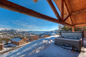 A wooden cabin with a hot tub and a view of snow-covered mountains. - Ski-in/Ski-out home w/private hot tub in Moonlight Basin - Cowboy Heaven Cabin - Wild West (Big Sky)