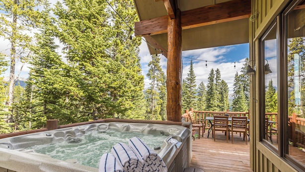 Ein Whirlpool auf einer Holzterrasse mit Blick auf einen Wald.