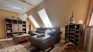 Una sala de estar estilo loft acogedora con un sofá de cuero oscuro, una mesa de centro de madera y un ventanal con tragaluces.