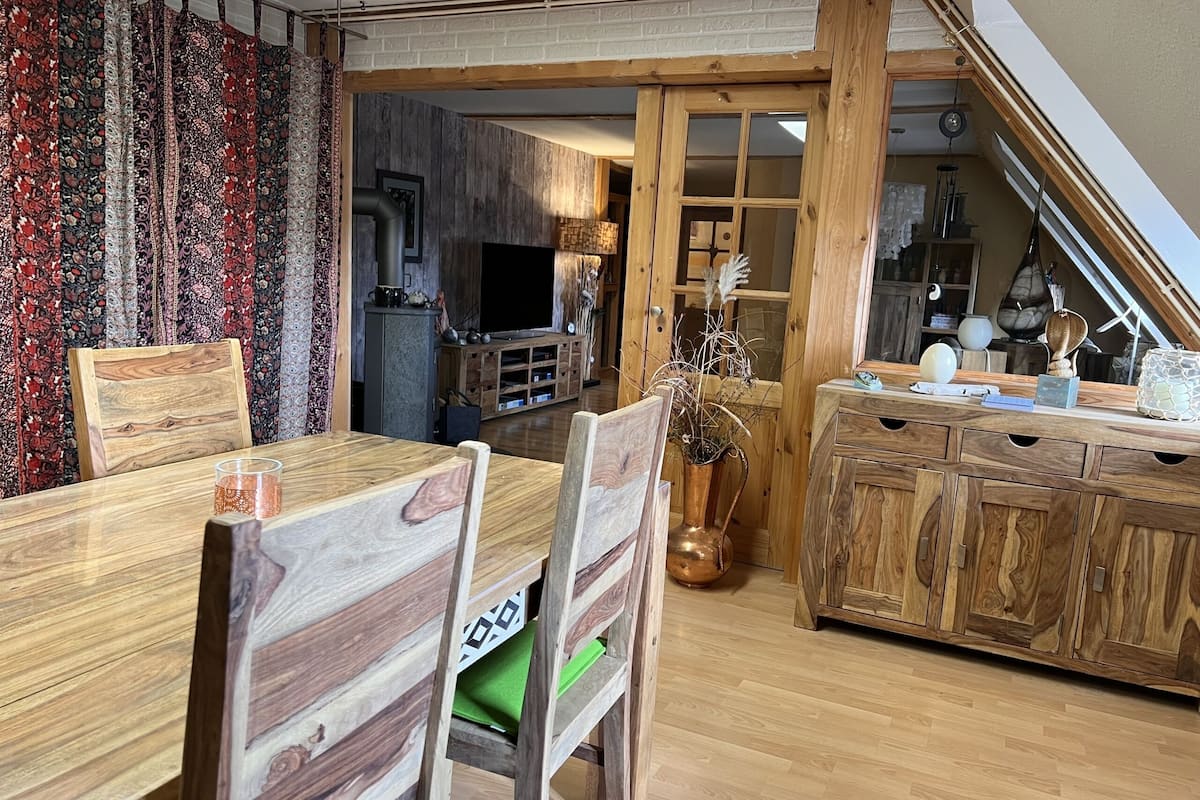 Un coin repas avec des meubles en bois, une table avec un plateau en verre et un vase contenant des plantes séchées.