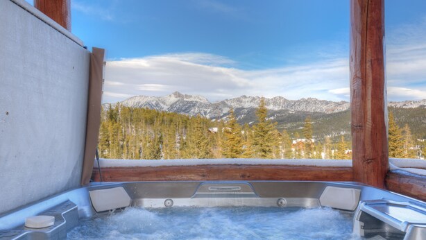 A hot tub with a mountain view, wooden beams, and a clear sky. - Ski-in/ski-out home w/private hot tub in Moonlight Basin - Saddle Ridge - Montana Mountain Chalet (Big Sky)