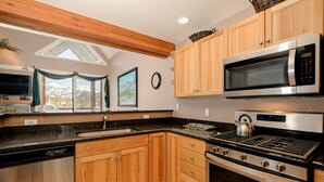 A modern kitchen with wooden cabinets, a stainless steel microwave, a gas stove, and a dishwasher. - Ski-in/ski-out home w/private hot tub in Moonlight Basin - Saddle Ridge - Montana Mountain Chalet (Big Sky)