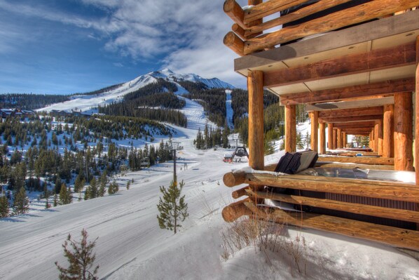 Una cabaña de madera con vistas a una montaña nevada y una pista de esquí.