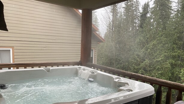Ein Whirlpool auf einer Holzterrasse mit Blick auf einen Wald.