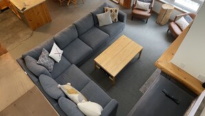 Ein modernes Wohnzimmer mit einem grauen Ecksofa, einem Holztisch und einem Essbereich mit einem Holztisch und Stühlen.