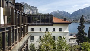 Un edificio moderno con un balcón de cristal que da a un lago y montañas.