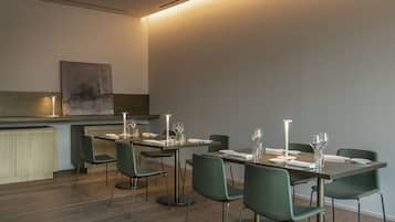 A modern dining area with a long table, green chairs, and a minimalist design.