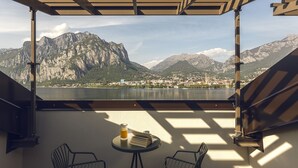 Una terraza con mesa y sillas, con vistas a un paisaje montañoso y un cuerpo de agua.