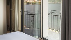 A hotel room with a large sliding glass door leading to a balcony with a mountain view. - Hotel Promessi Sposi (Malgrate)